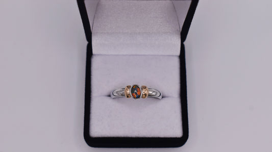 A gorgeous Lightning Ridge Black Opal set in 925 Sterling Silver and complimented on both sides by 14ct Gold melted down from an Old Antique Pocket Watch. This ring is stunning and sets off a charming beauty. It's many rich colours dance in the natural light and is definitely a timeless piece of perfection.  Size- S  Please note that colours of the opal may vary due to lighting and angles. As it is Opal, that is normal and expected.